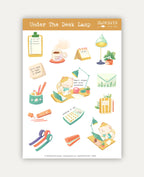 An image of a sticker sheet titled "Under The Desk Lamp" featuring various cute, productivity-themed illustrations on a white background with a light brown header. The central design shows a little cat focused on writing at its desk under a green lamp, next to the text *"Small steps are also progress"*. Other stickers include another cat working on a laptop, a warm coffee cup (*"coffee first"*), a clipboard to-do list, a calendar, washi tape rolls, a calculator, a planner, a pen holder, and a note that read